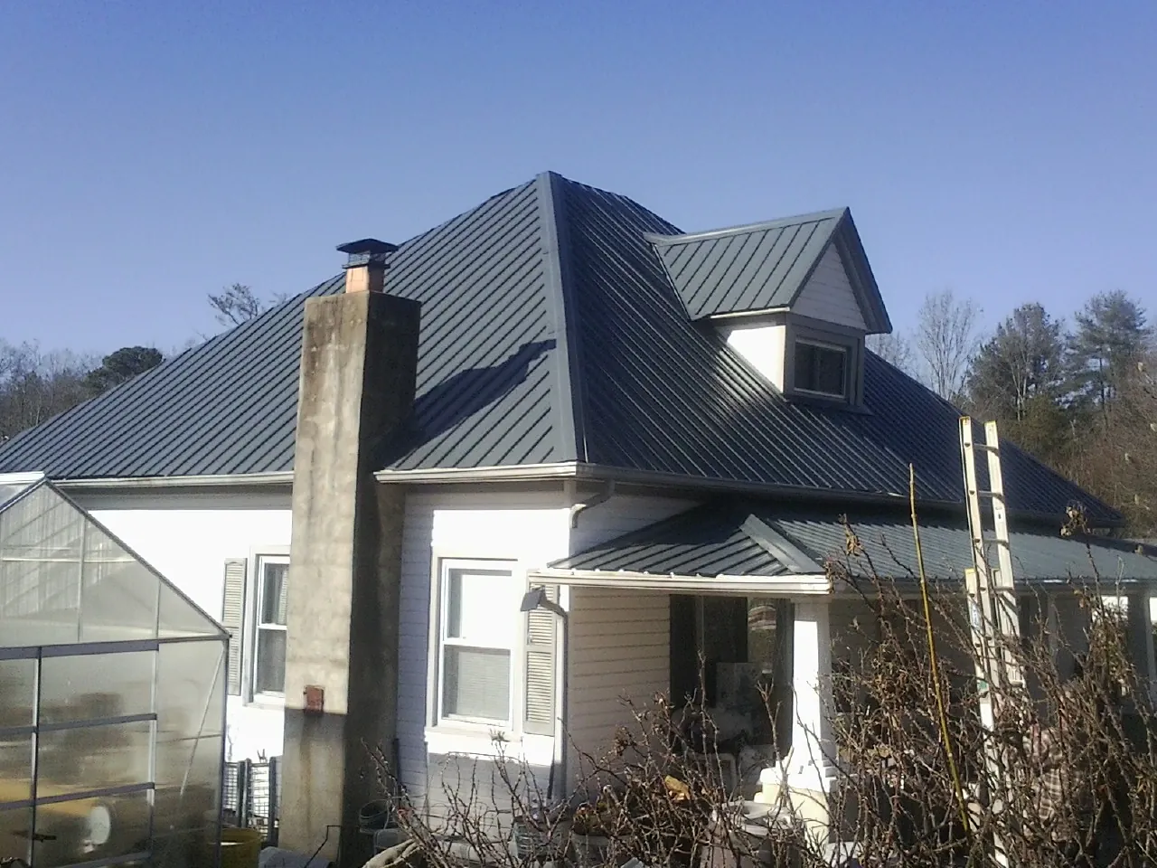 Dark blue standing seam metal roof on a white farmhouse with dormer — Slate & Tile Roof Repair by Roofing Brothers in Newport Coast