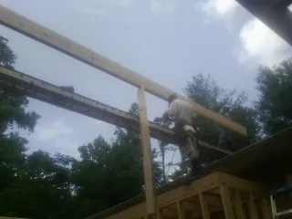 Carpenter setting a ridge beam over a new addition frame — Ice Dam Removal by Roofing Brothers in Newport Coast