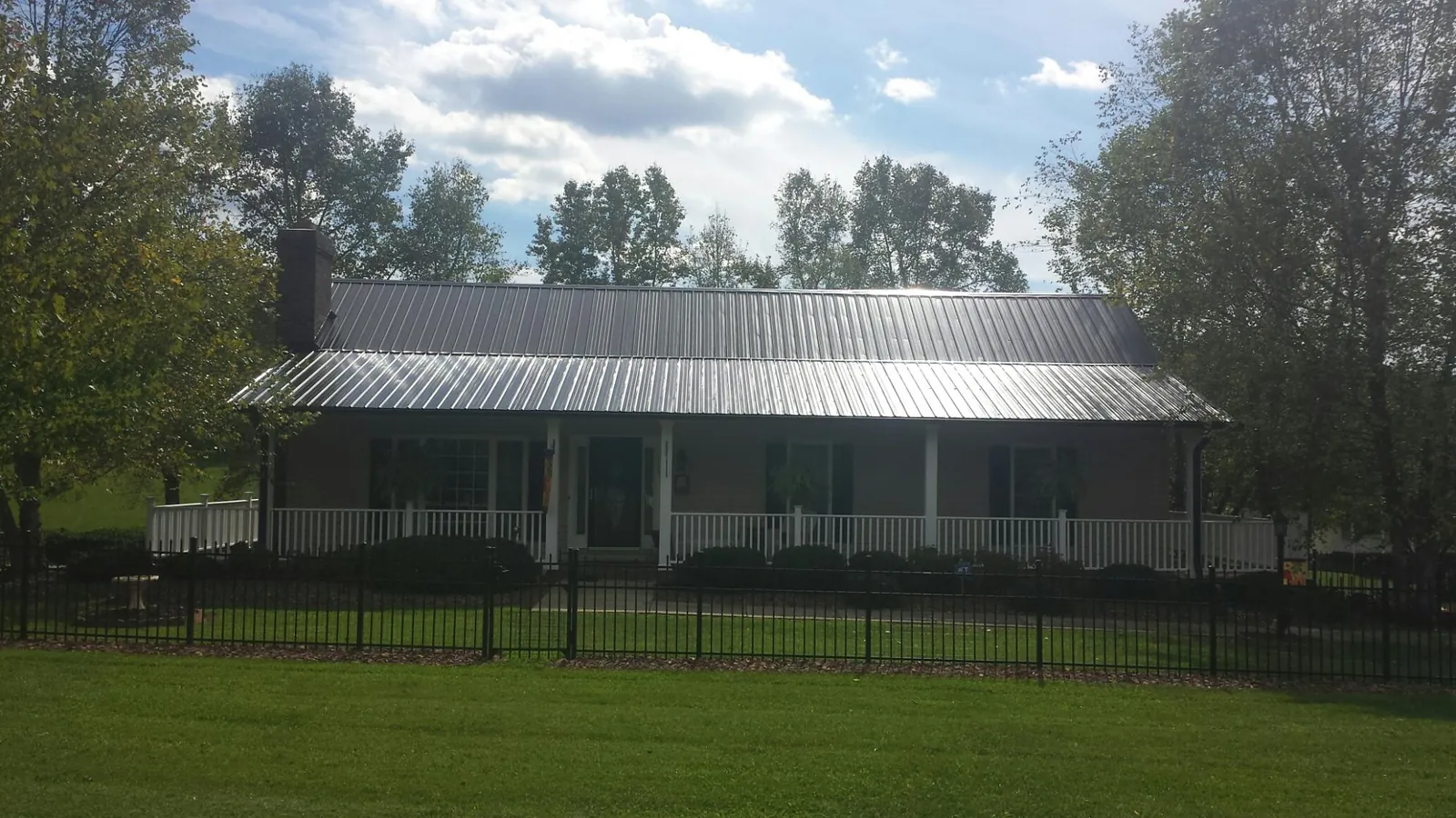 Gray metal roof on a brick ranch with a full width front porch — Gutter Guard Installation work by our crew in Newport Coast