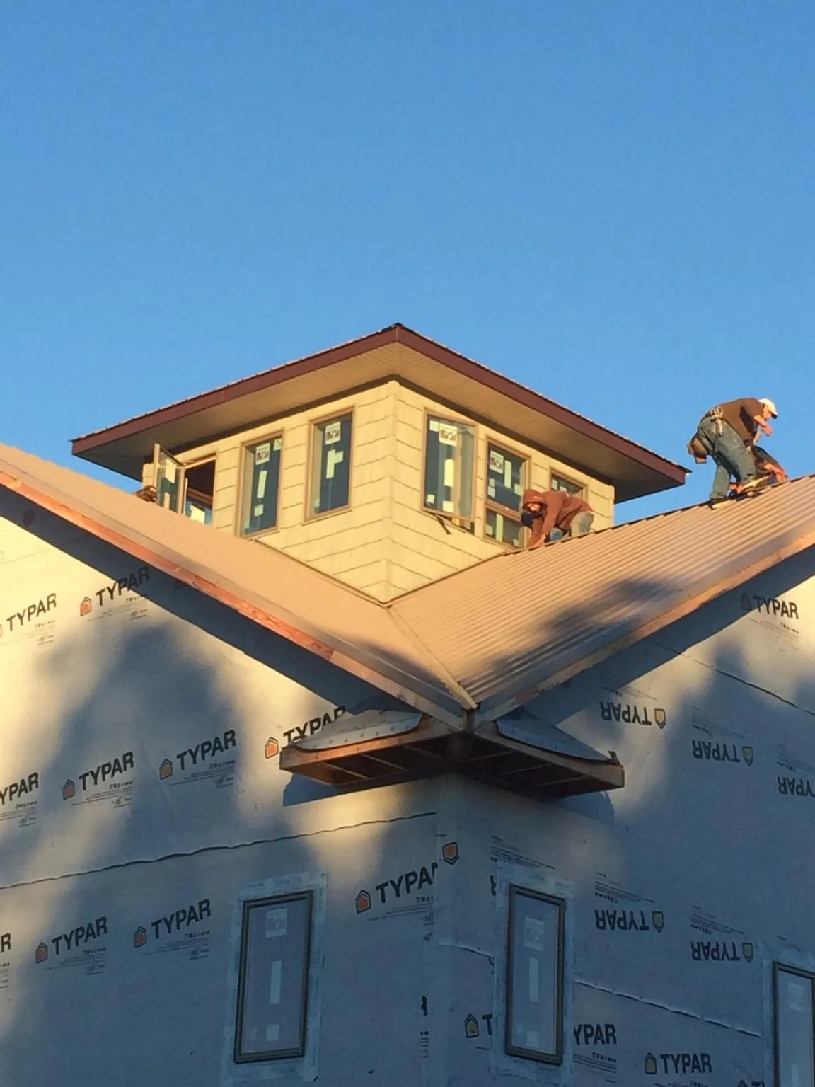 Roofers working around a rooftop cupola on a new metal roof at sunset — Roof Waterproofing in Newport Coast by Roofing Brothers